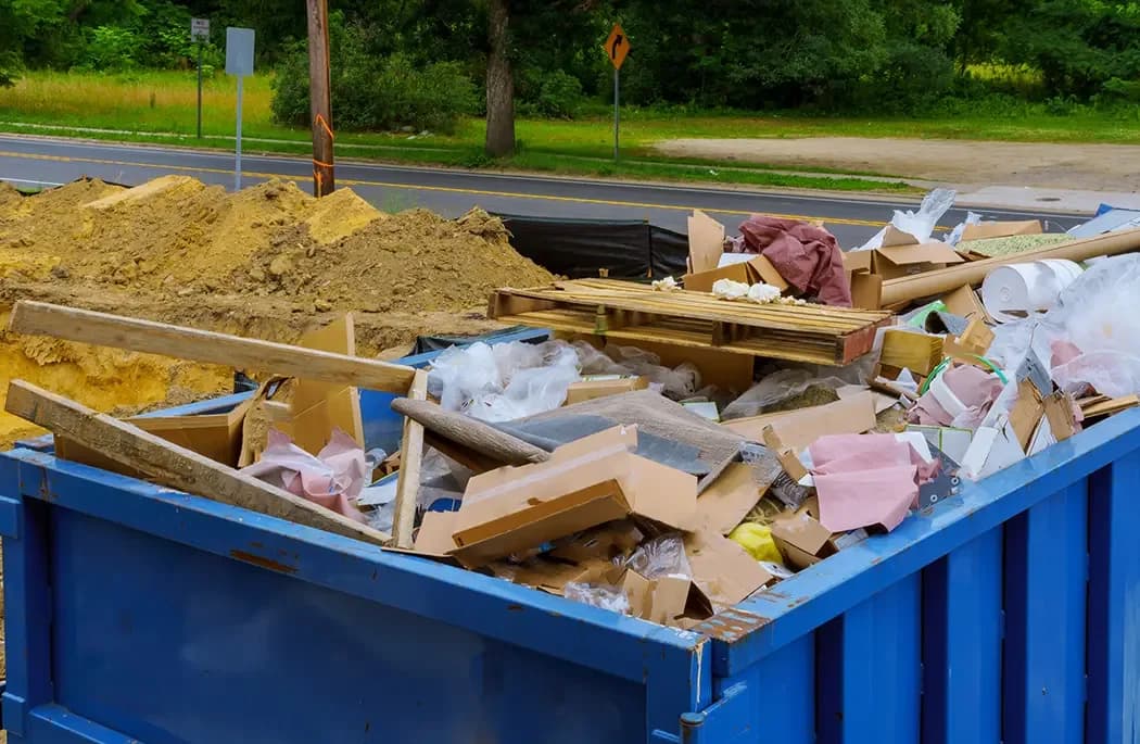 A dumpster loaded with boxes, lumber and debris from a cleanout